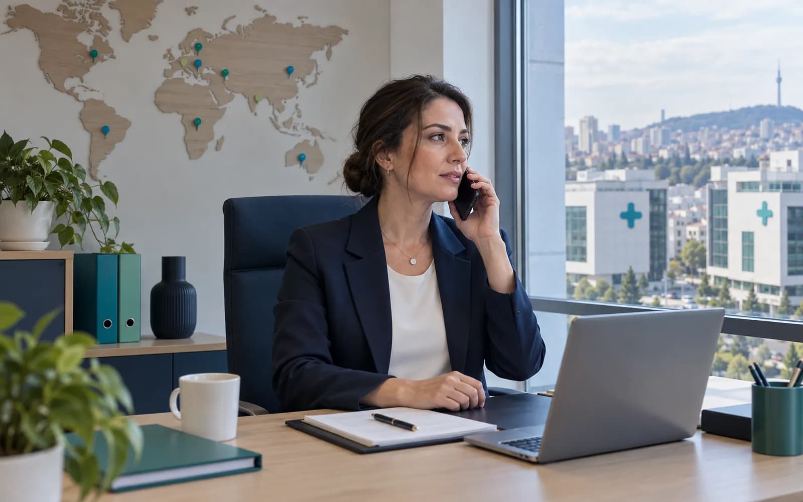 A manager on a phone call at a city-view window, two clinic facades visible