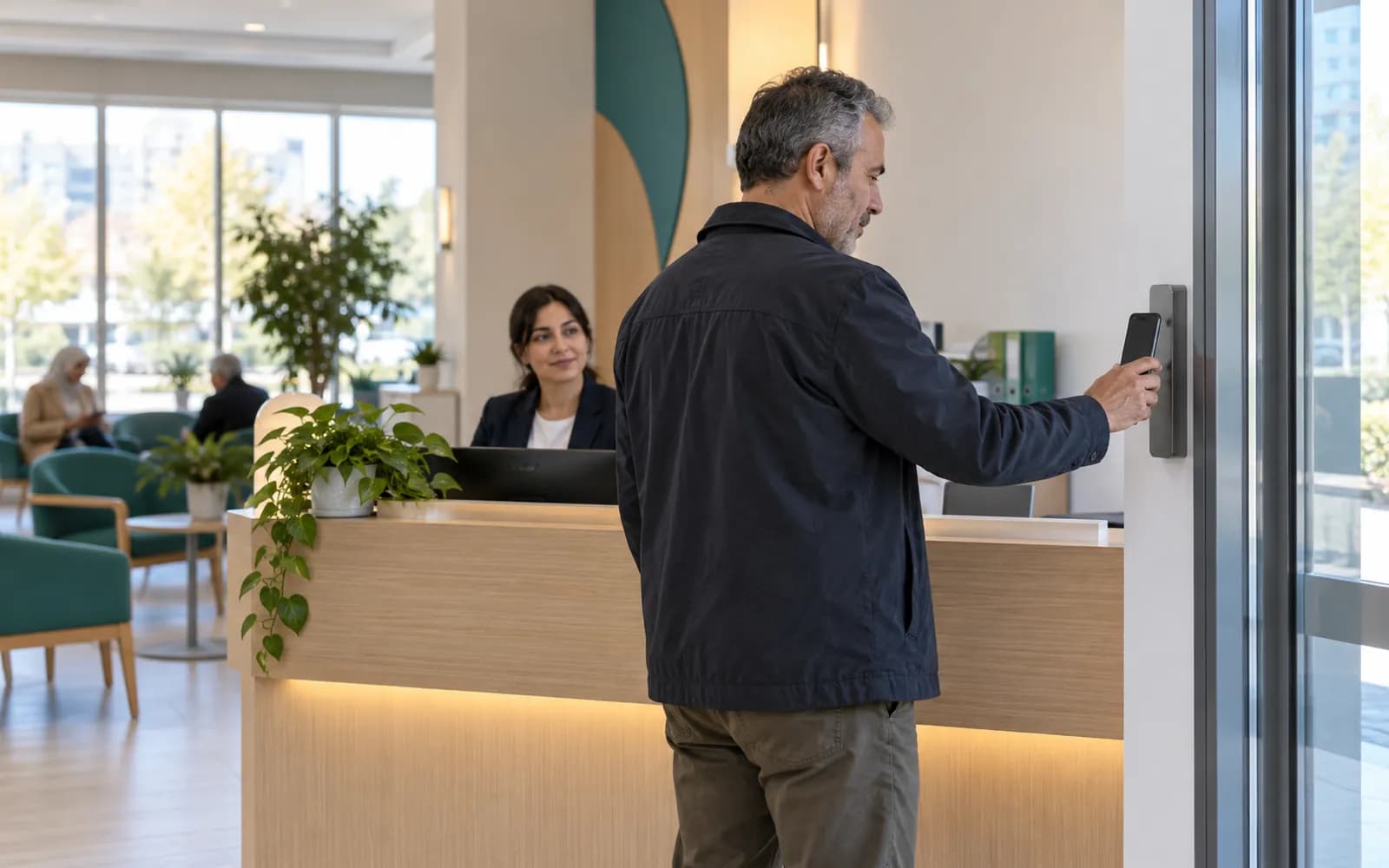 Girişte telefonunu okutarak geldiğini bildiren hasta, arkada karşılayan ön büro görevlisi