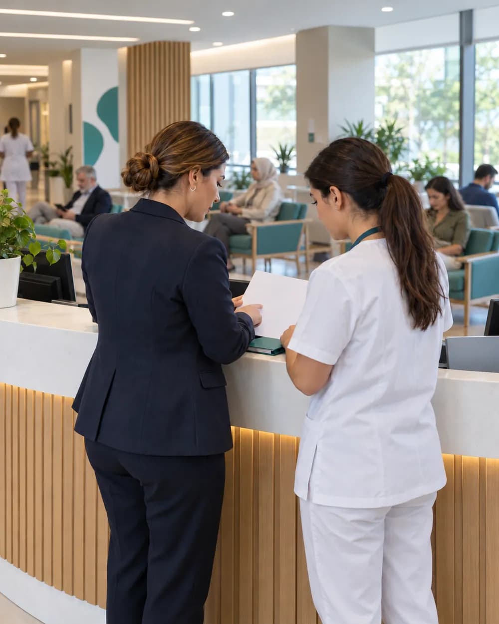 Resepsiyon tezgahında basılı çizelgeyi inceleyen klinik yöneticisi ve ön büro sorumlusu