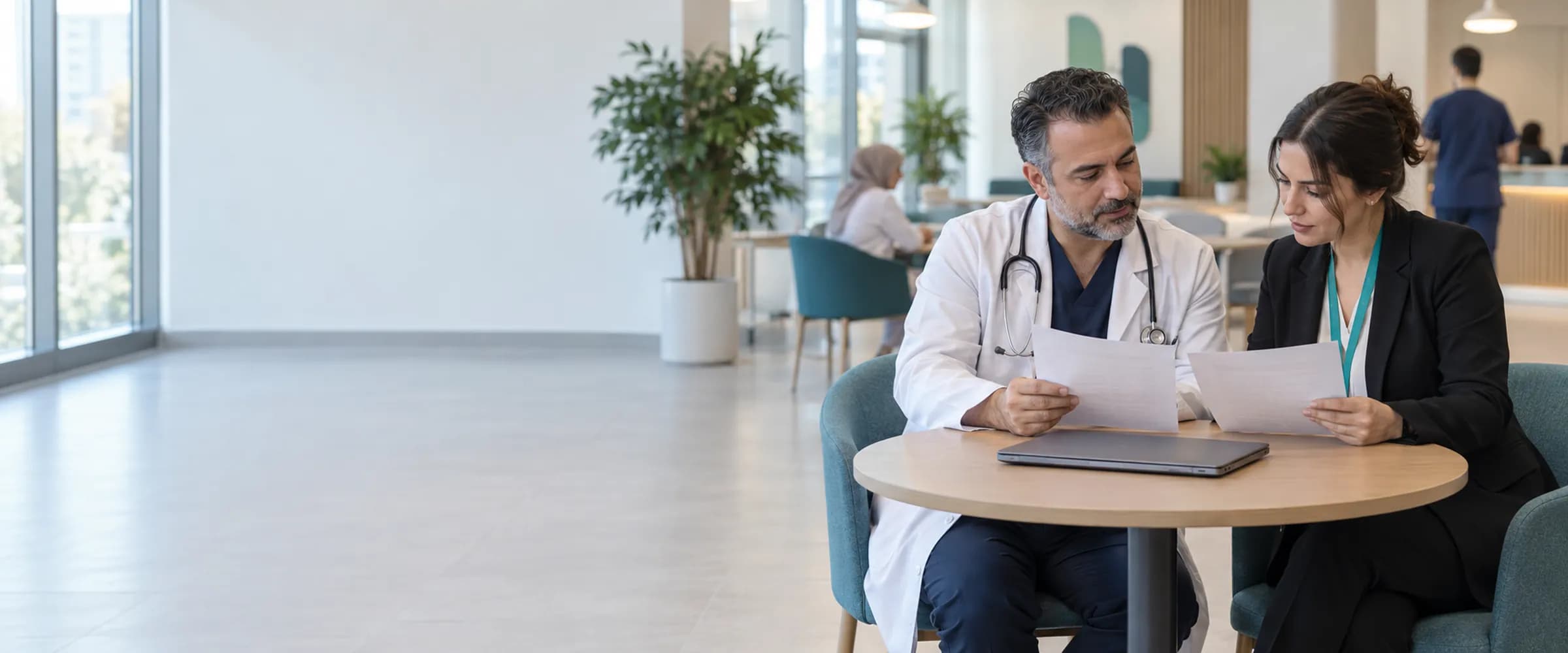 Klinikte kafe tarzı masada basılı iki kâğıdı karşılaştıran hekim ve klinik yöneticisi