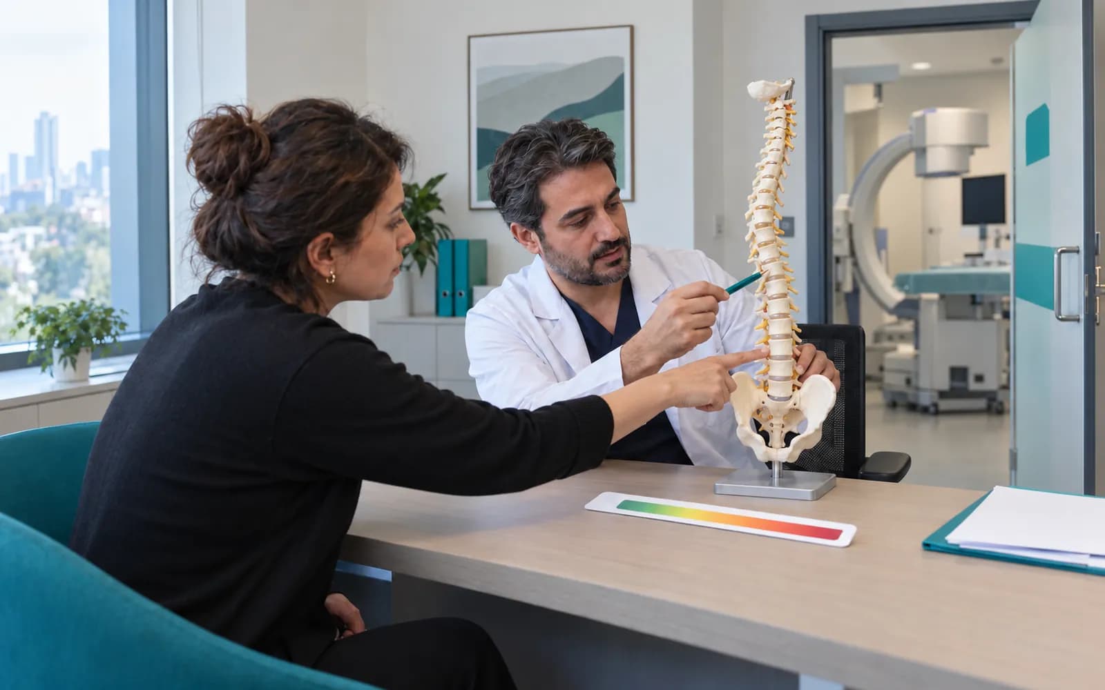 Hastasına omurga modelinde bölgeyi gösteren ağrı hekimi; masada rakamsız ağrı ölçeği cetveli
